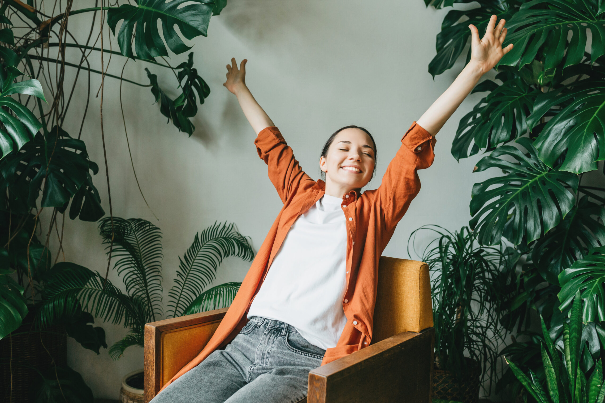 Eine junge Frau entspannt sich im schönen Garten ihres Hauses. Eine Floristin und Gärtnerin ruht sich nach der Pflege ihrer Zimmerpflanzen aus. Wohlbefinden, Erholung und Work-Life-Balance